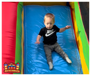 toddler sliding down a bounce house slide